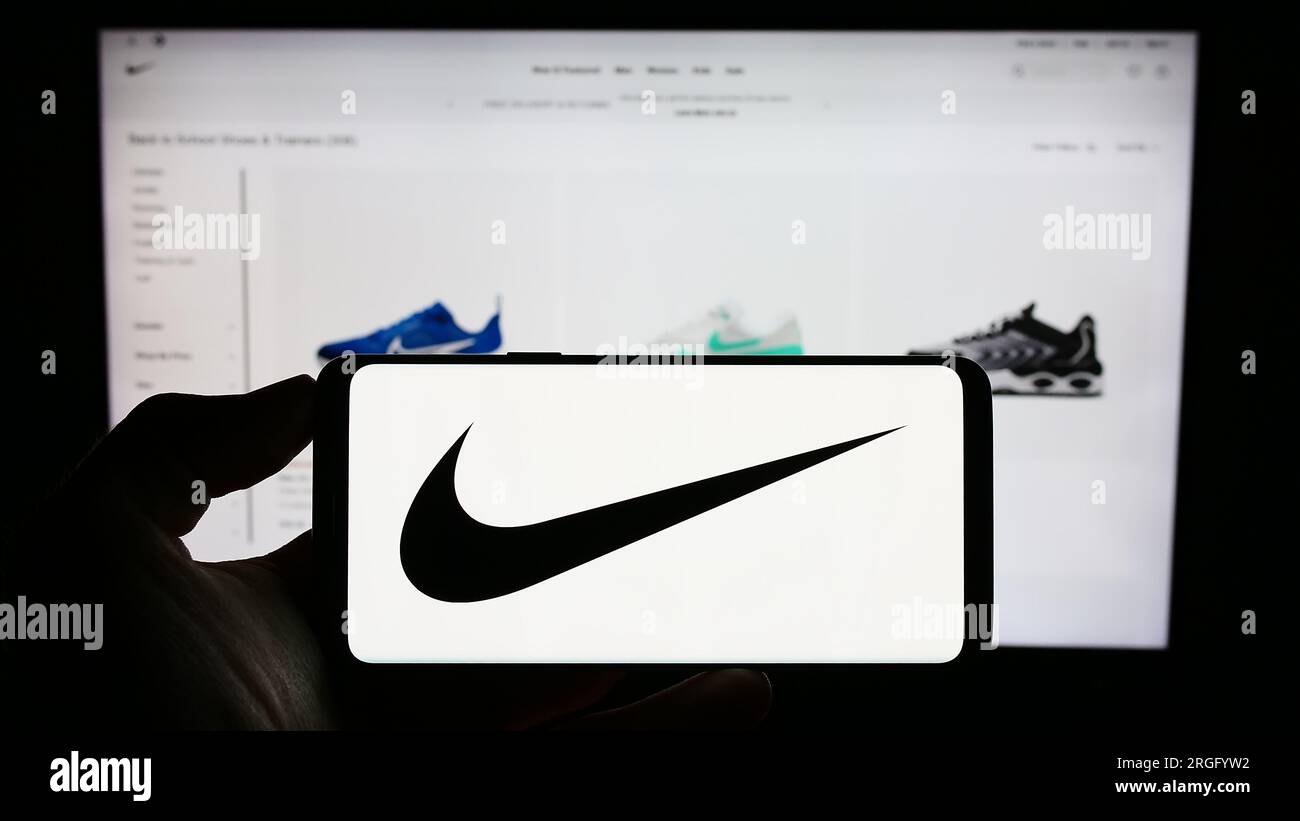 Persona che tiene il cellulare con il logo dell'azienda statunitense di abbigliamento sportivo Nike Inc. Sullo schermo davanti alla pagina Web aziendale. Concentrarsi sul display del telefono. Foto Stock