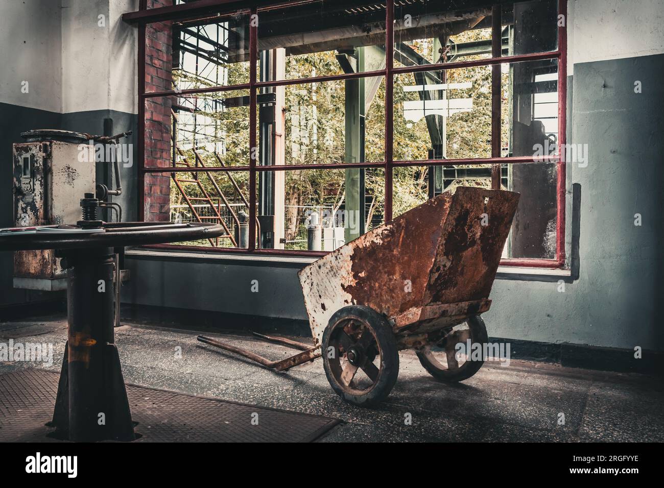 Carriola rugginita nel vecchio edificio della fabbrica Foto Stock