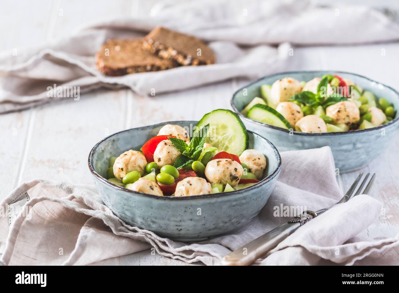 Insalata estiva con cetrioli, mini pomodori, mini mozzarella e soia su fondo di legno bianco Foto Stock