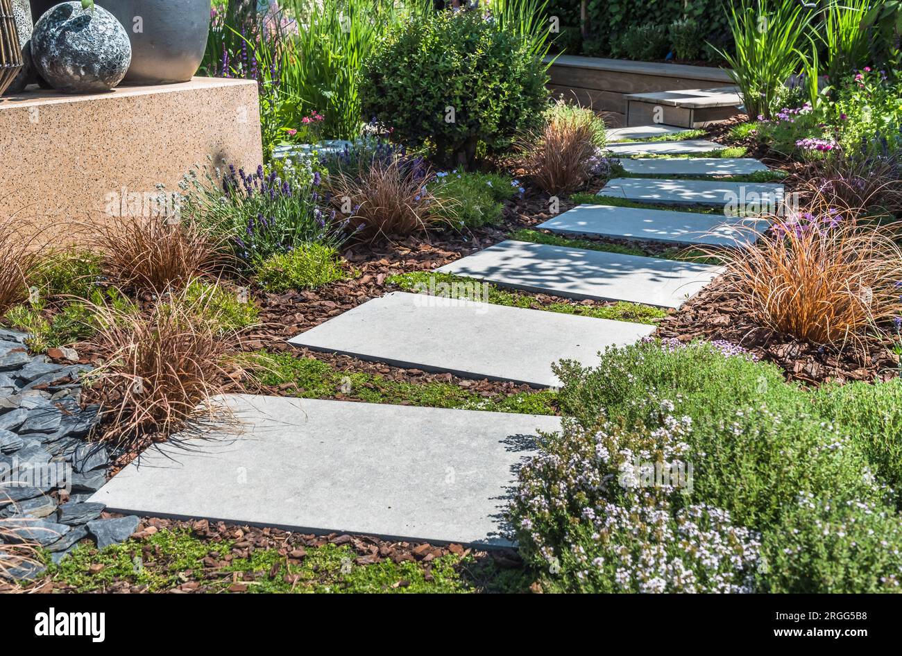 Sentiero con grandi lastre di pietra attraverso un giardino splendidamente piantato Foto Stock
