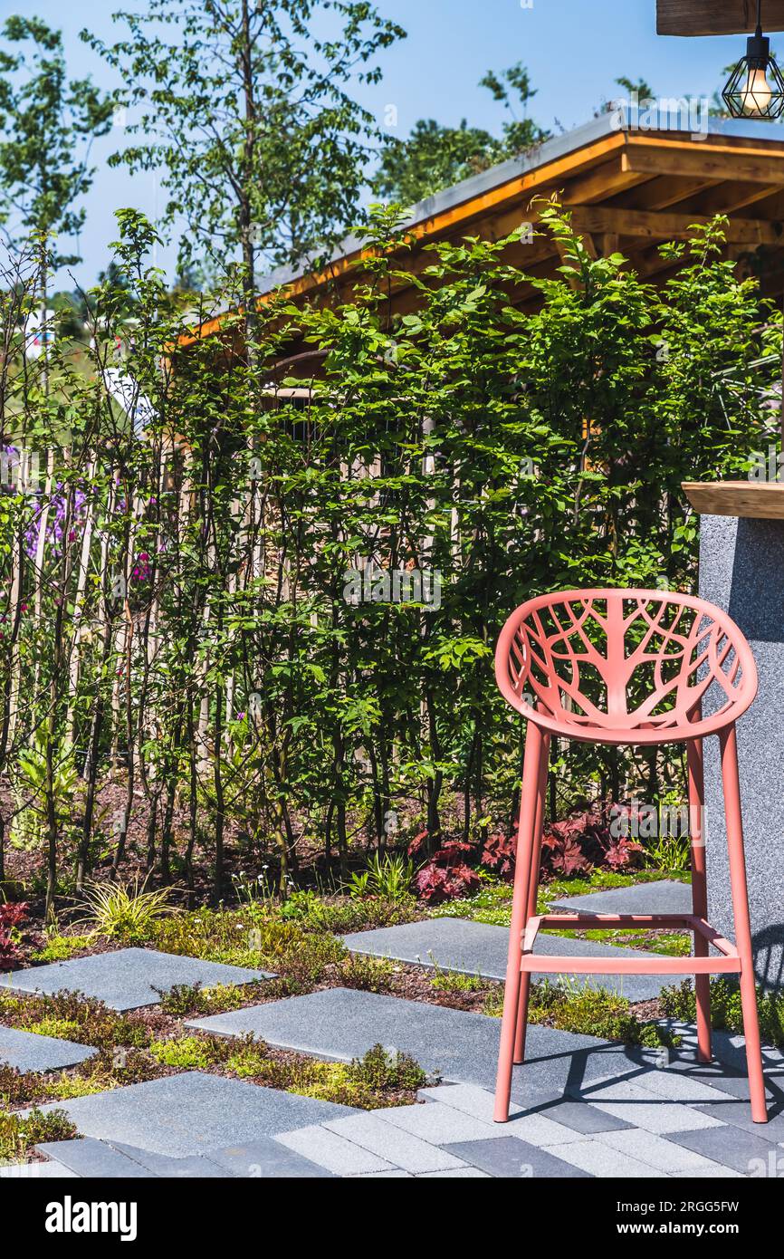 Giardino nuovo e moderno con pietre pavimentate e bar con sgabello da bar, verticale Foto Stock