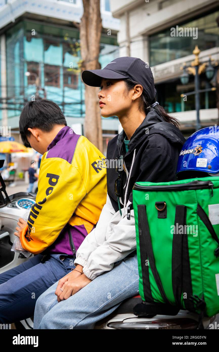 Un corriere thailandese si siede con la sua amica sulla sua bici facendo una pausa sulla sala Daeng Rd. Bangkok, Thailandia. Foto Stock