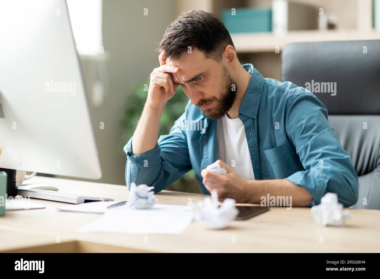 Arrabbiato e stressato, uomo d'affari che si prende gioco della carta mentre si è seduti alla scrivania in ufficio Foto Stock