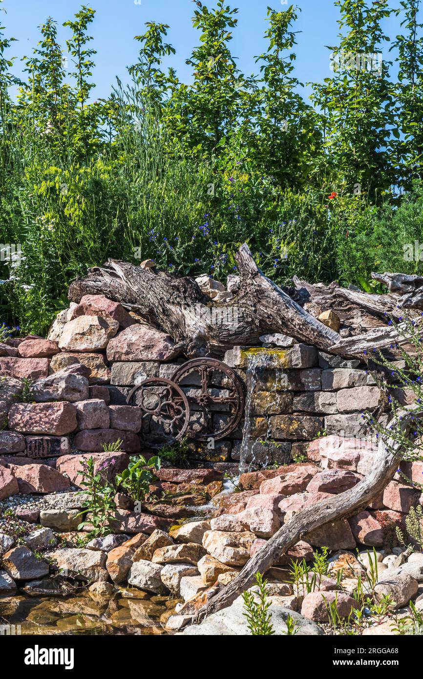 Giardino naturale con pietre, legno antico e corso d'acqua Foto Stock