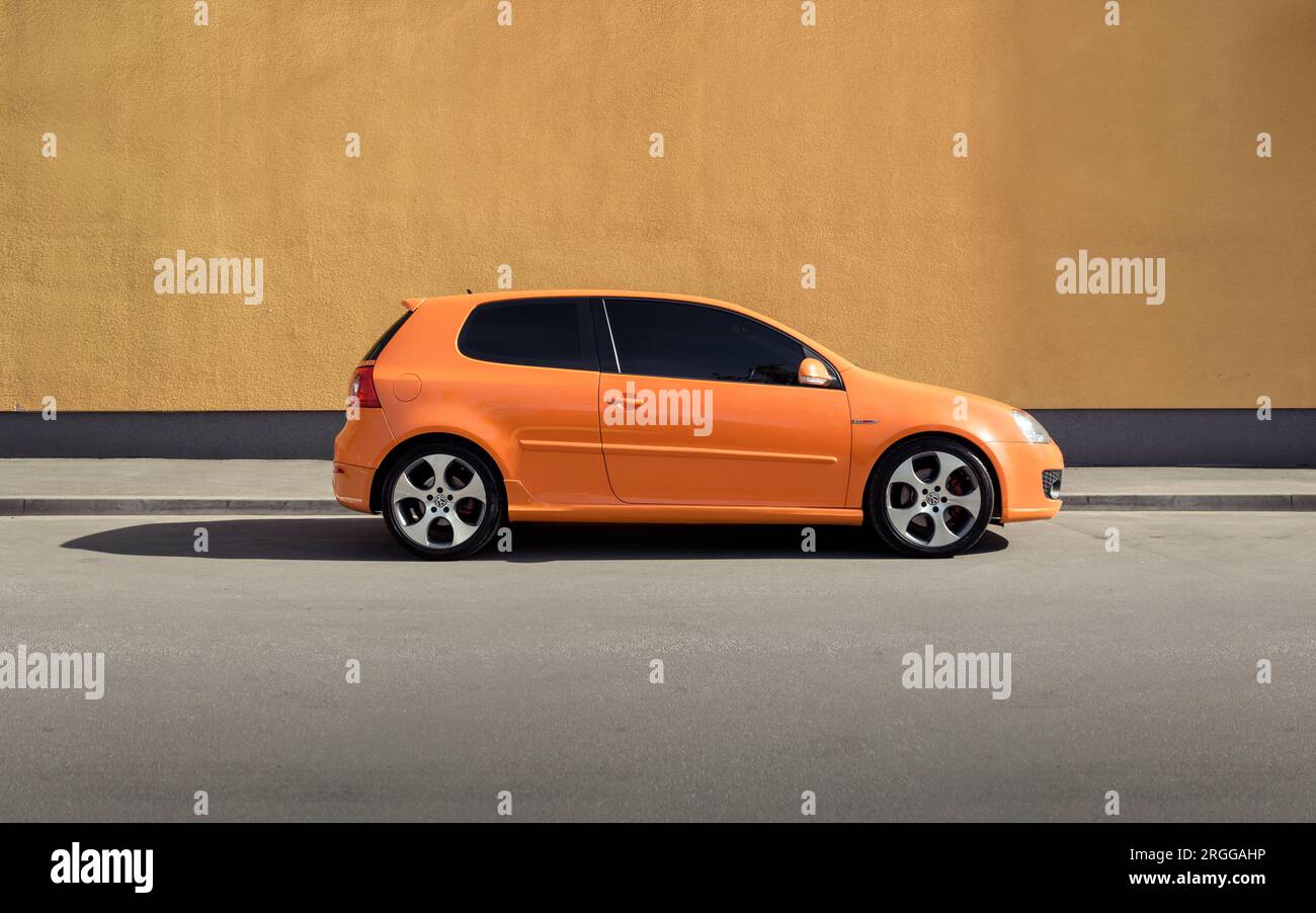 Orange Golf GTI di fronte al muro arancione in una giornata di sole Foto Stock