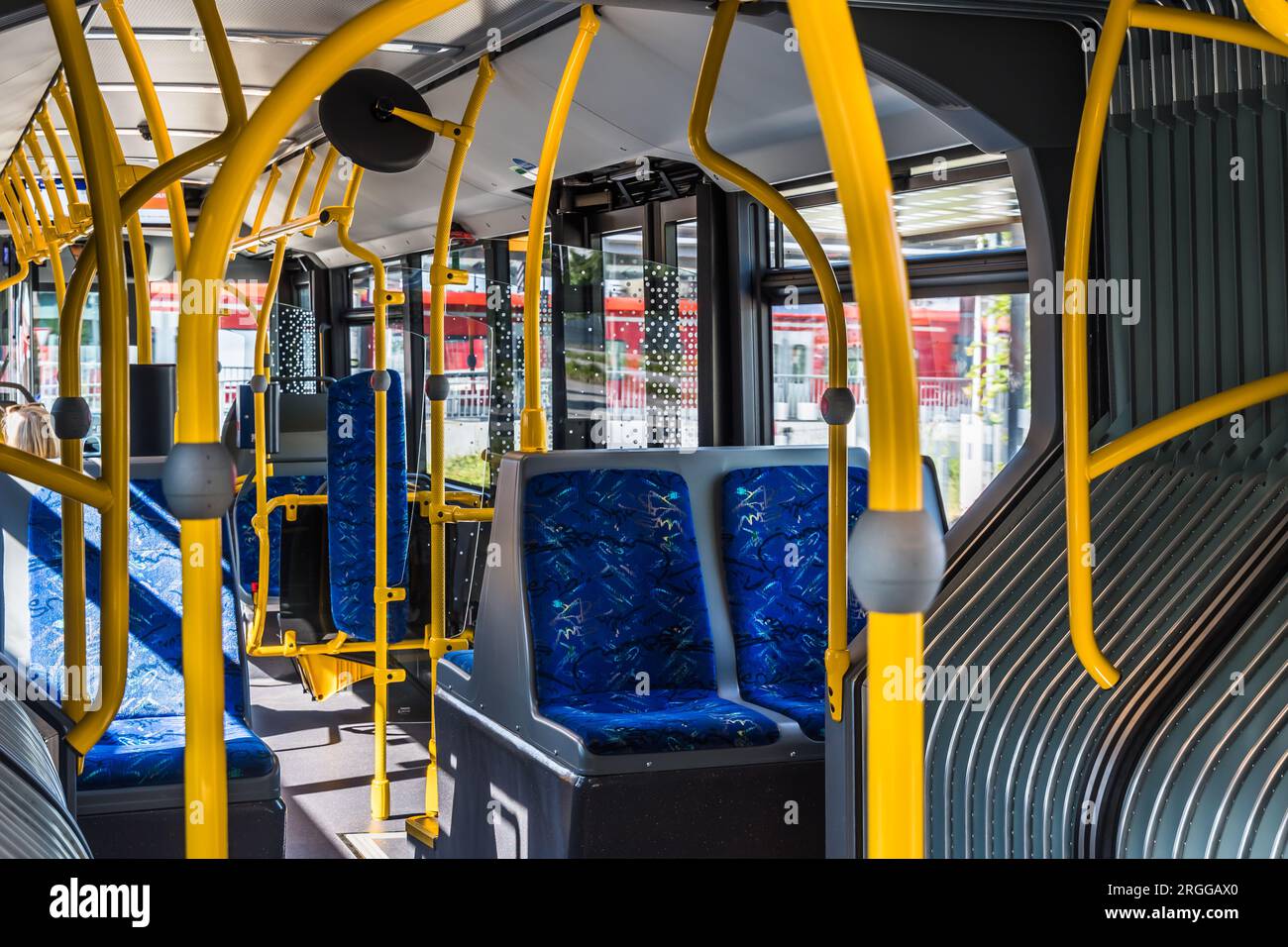 Design degli interni di un autobus moderno. Interno bus vuoto. Trasporti pubblici in città. Trasporto passeggeri. Autobus con sedili blu e corrimano gialli. Foto Stock