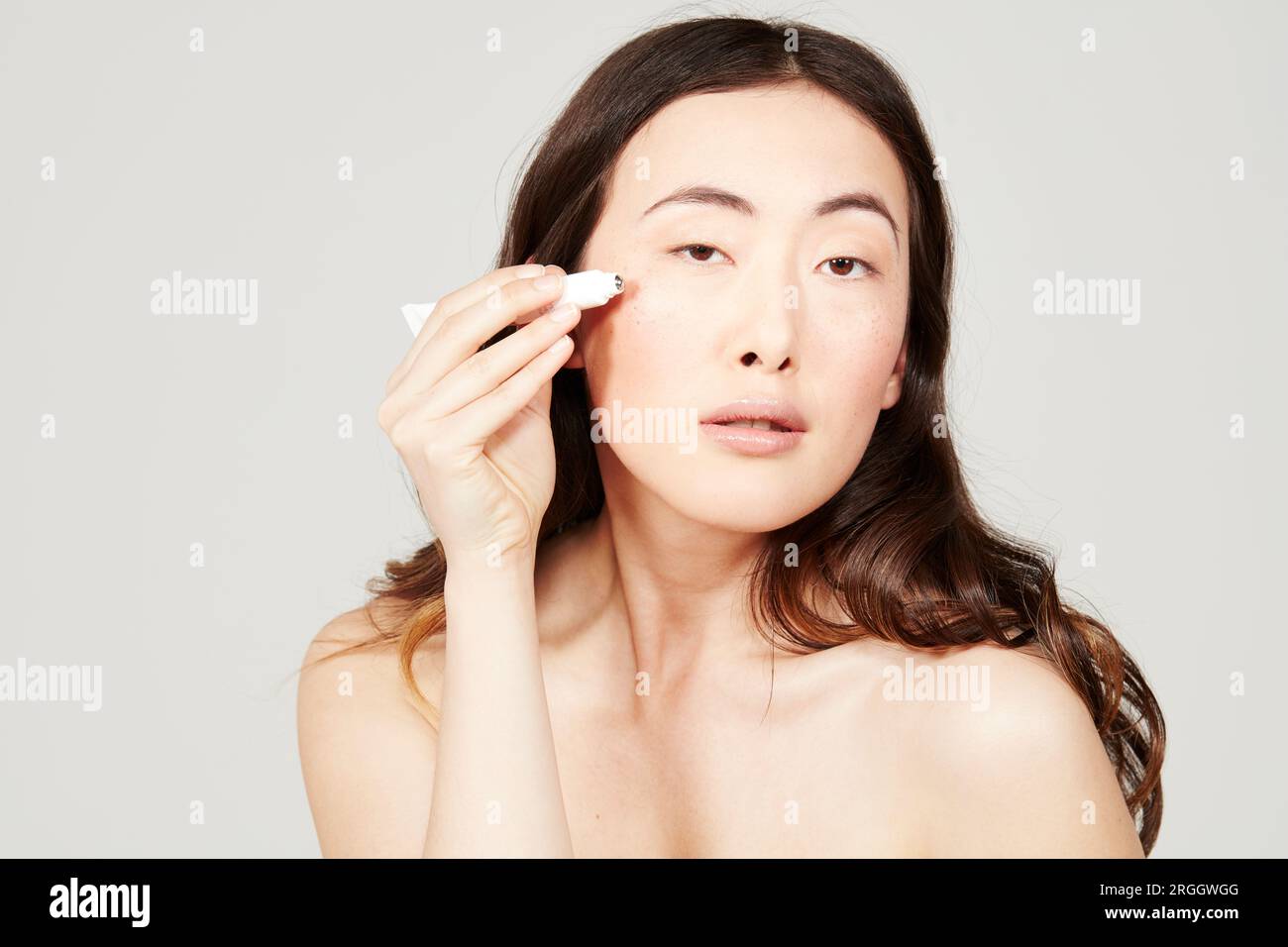 Giovane donna l'applicazione di crema per il viso dal tubo Foto Stock