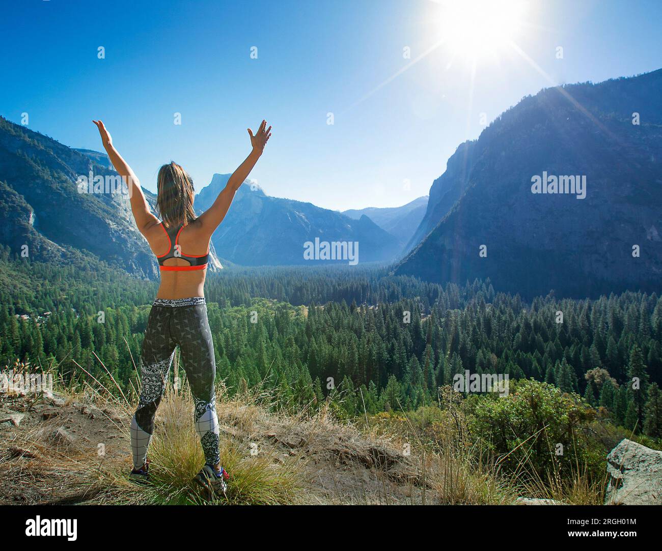 Donna che festeggia in un paesaggio montuoso Foto Stock