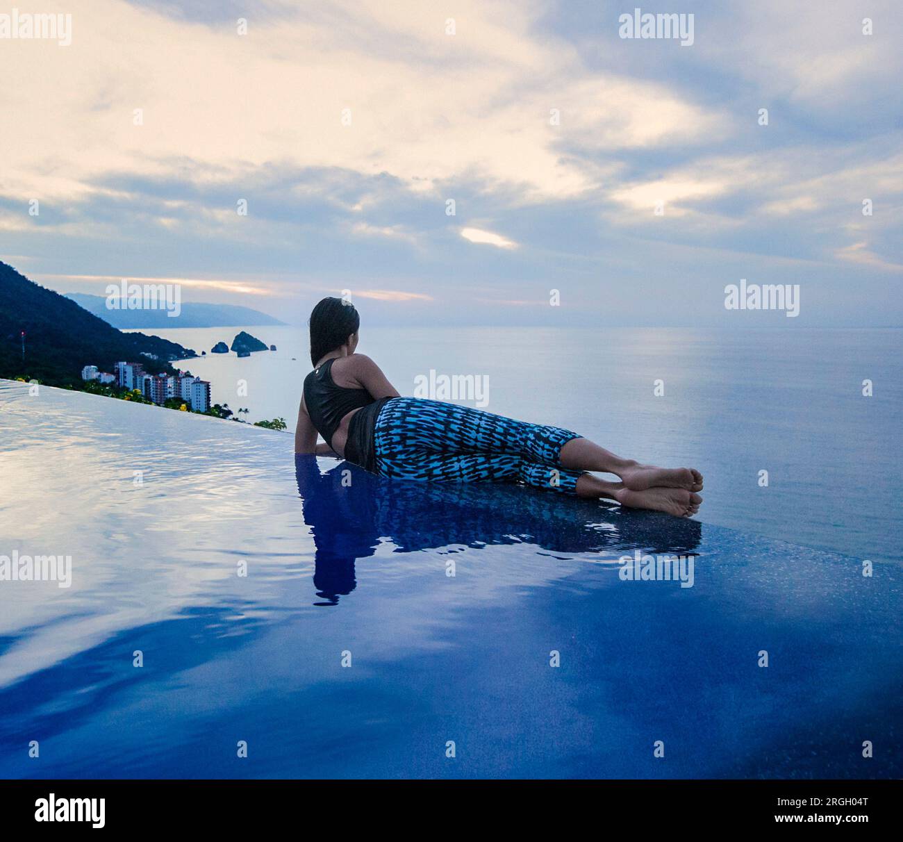 Persona che si rilassa presso una piscina a sfioro al tramonto Foto Stock