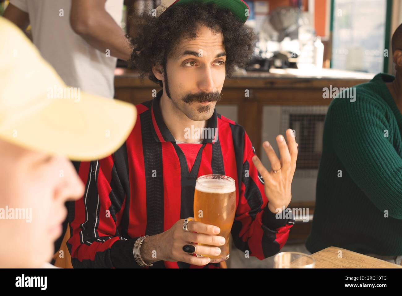 Uomo con baffi che tiene un bicchiere di birra in un bar Foto Stock