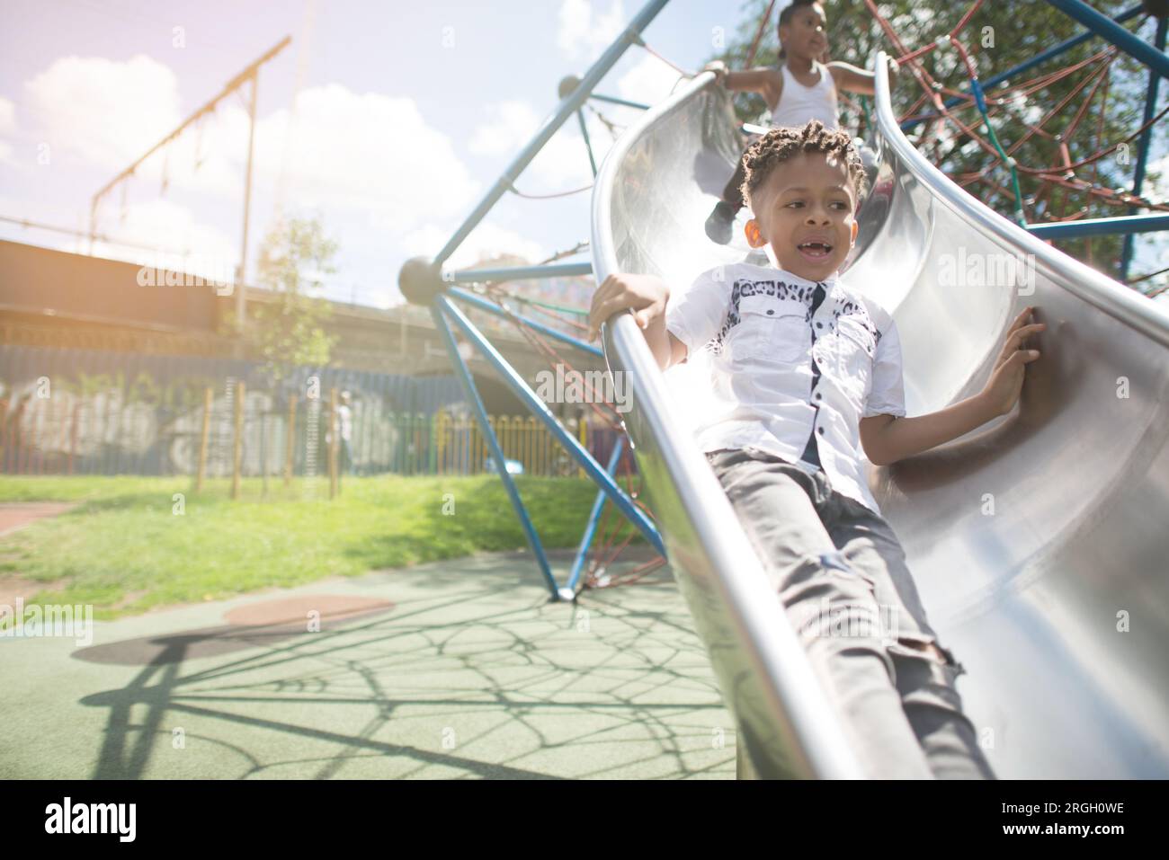 Il bambino scivola giù da uno scivolo per il parco giochi. Foto Stock