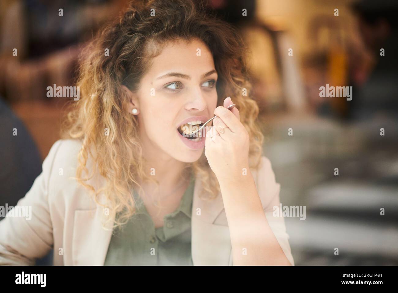 Giovane donna di mangiare la torta dietro la finestra cafe Foto Stock