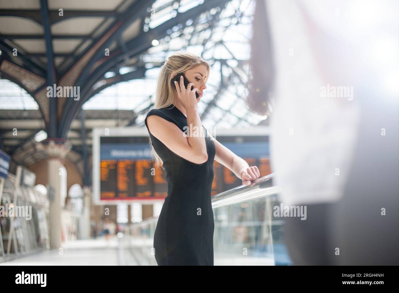 Donna d'affari al telefono alla stazione ferroviaria Foto Stock