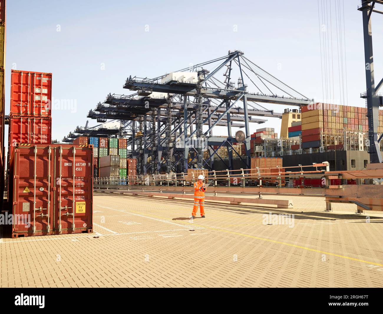 Lavoratore Dock esaminando pila dei contenitori di carico nel porto di Felixstowe, Inghilterra Foto Stock
