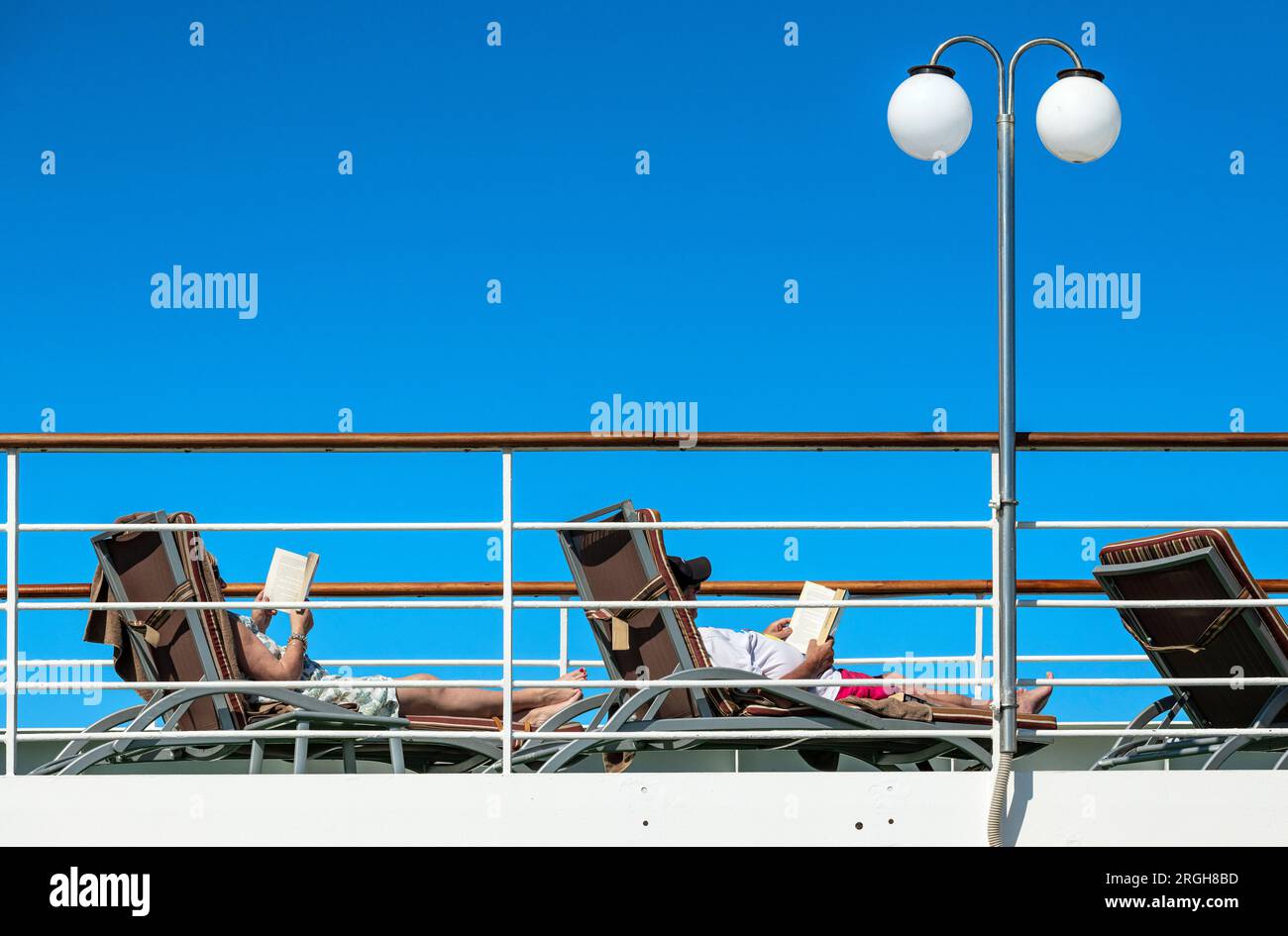 I vacanzieri leggono un libro sul ponte della nave da crociera. Foto Stock