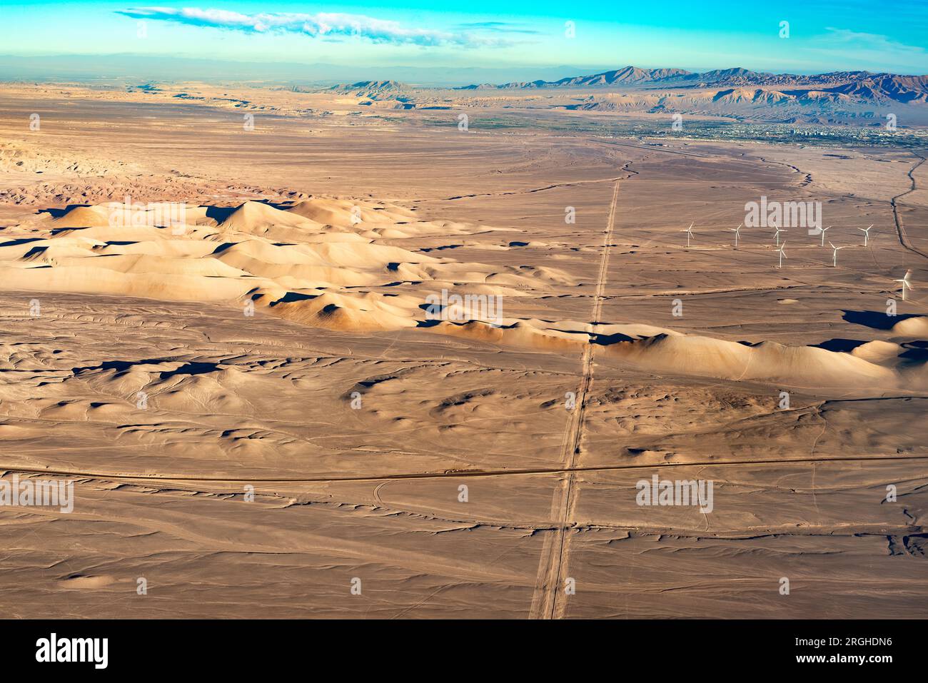 Vista aerea del deserto di Atacama con la città di Calama sullo sfondo e una strada e turbine eoliche in primo piano Foto Stock