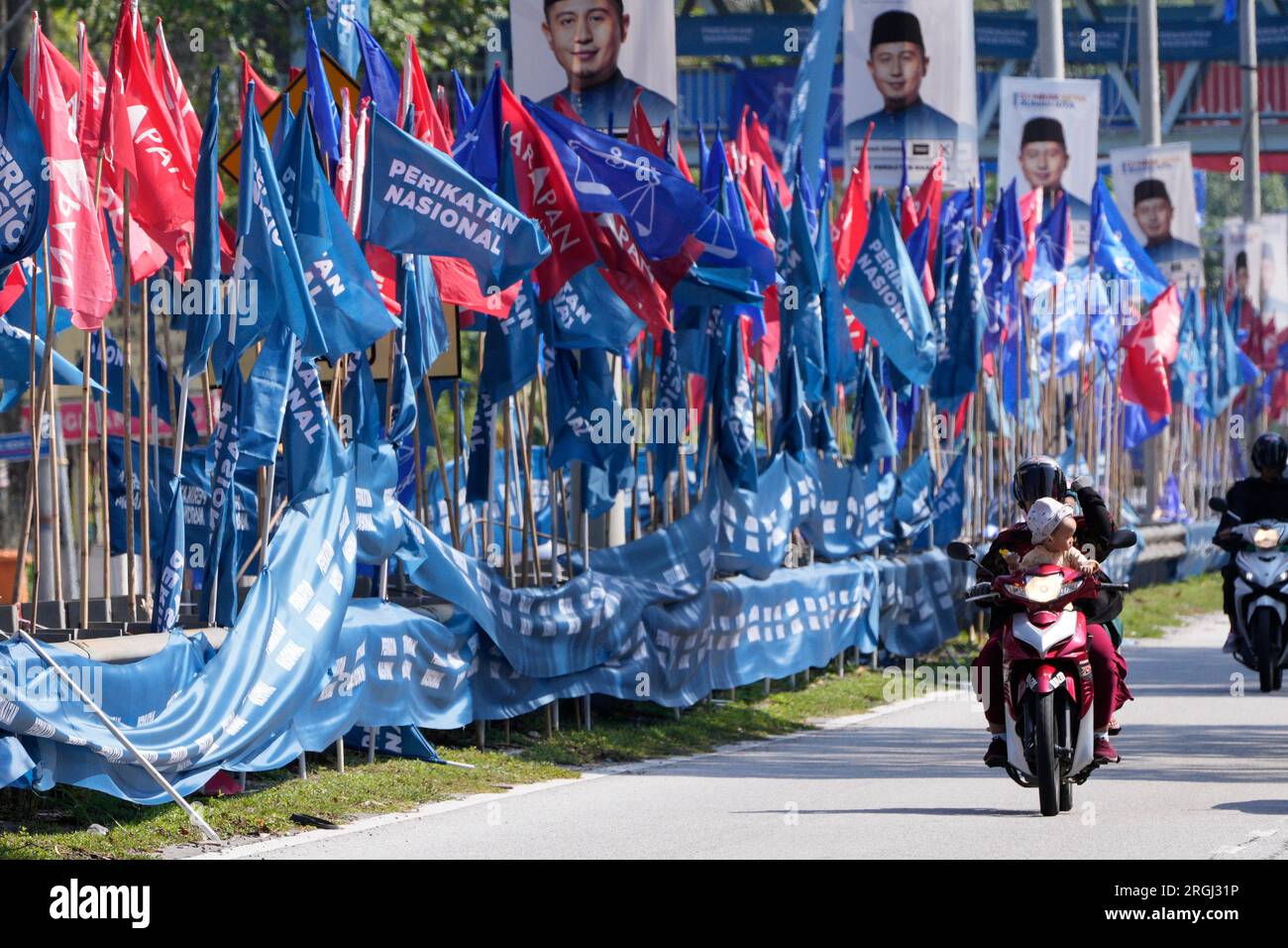 Motorcyclists pass by campaign flags ahead of the state election in Gombak, on the outskirts of Kuala Lumpur, Malaysia Wednesday, Aug. 9, 2023. Six of Malaysia’s 13 states are holding elections now because the local governments refused to call for early polls at the same time as general elections in November. They cited the need to prepare for floods during the year-end annual monsoon season. (AP Photo/Vincent Thian) Foto Stock