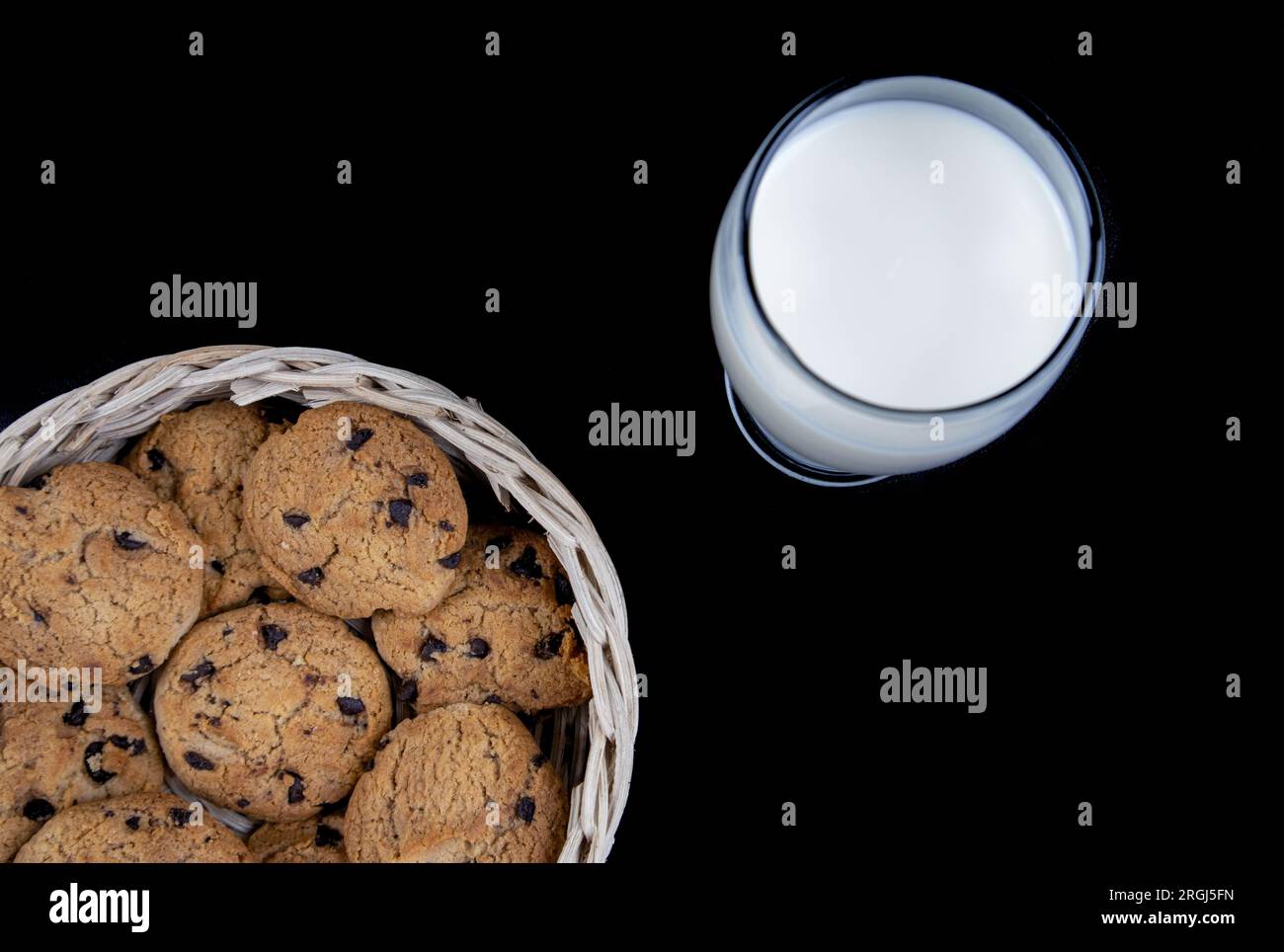 Biscotti con latte fresco e chip di cioccolato in un cestino di bambù isolato su fondo nero Foto Stock