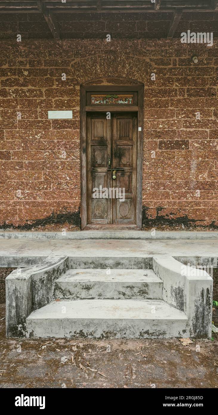 un ingresso ad una casa vecchio stile con una porta in legno d'epoca e pareti fatte di mattoni rossi Foto Stock