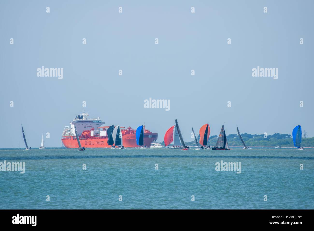 Barche a vela colorate con nel Solent Hampshire con una petroliera e l'Isola di Wight sullo sfondo Foto Stock