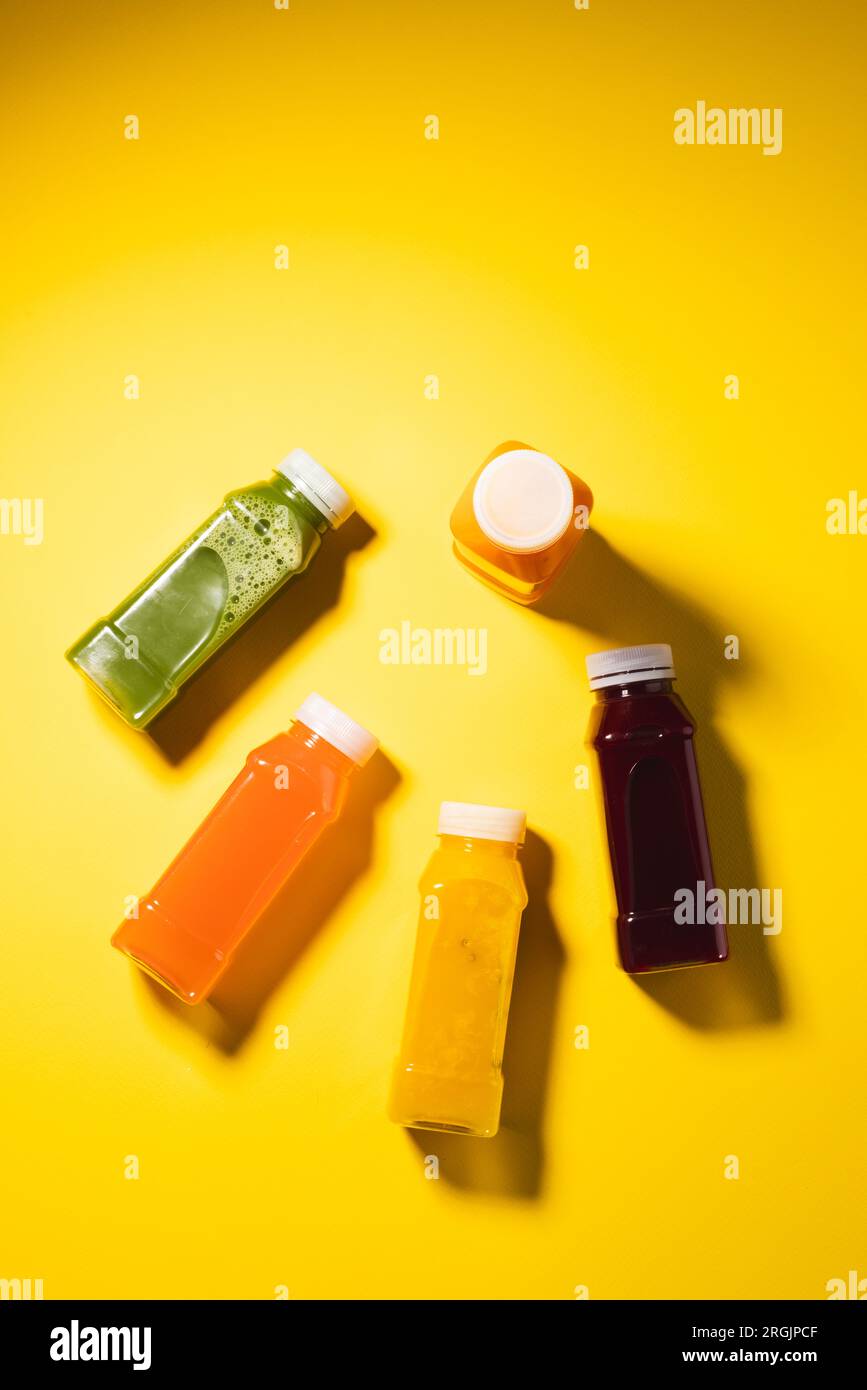 Primo piano dei flaconi di plastica con succo fresco e spazio per la copia su sfondo giallo Foto Stock