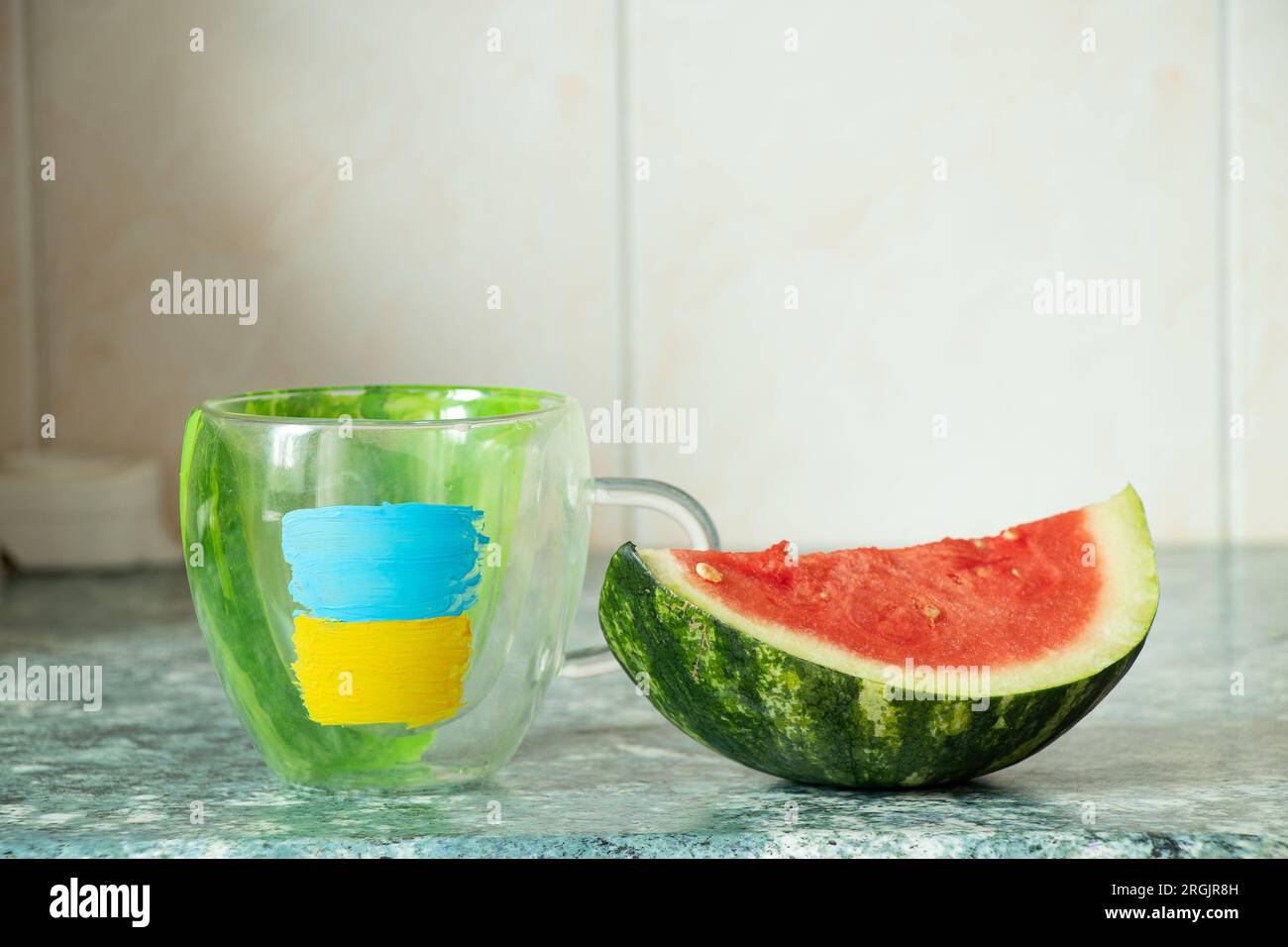 Una tazza con una bandiera dipinta dell'Ucraina e un anguria affettata accanto dalla città di Kherson in Ucraina nella cucina di una casa in Ucraina Foto Stock