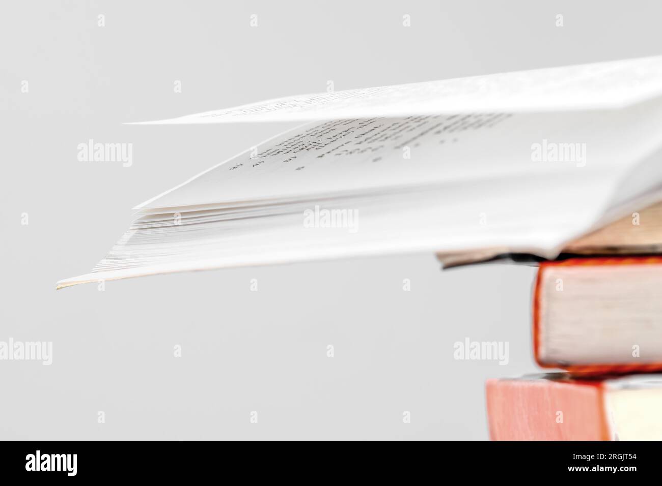 Pila di libri in biblioteca, uno dei quali aperto in alto, dorso di libri multicolore. Concetto di istruzione. Foto Stock