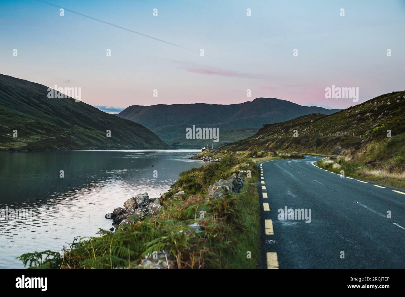 Connemara loop o strada mentre il sole tramonta sul fiordo di Killary, il Connemara National Park. Il tramonto dell'Irlanda occidentale mentre la strada panoramica N59 si estende sul mare Foto Stock