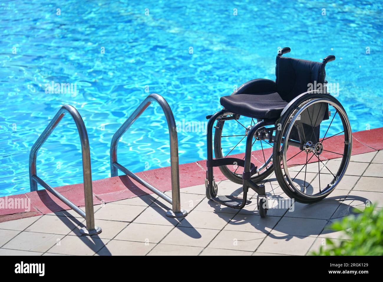 Sedia a rotelle vuota in piscina per riabilitazione di persone con disabilità in acqua. Foto Stock
