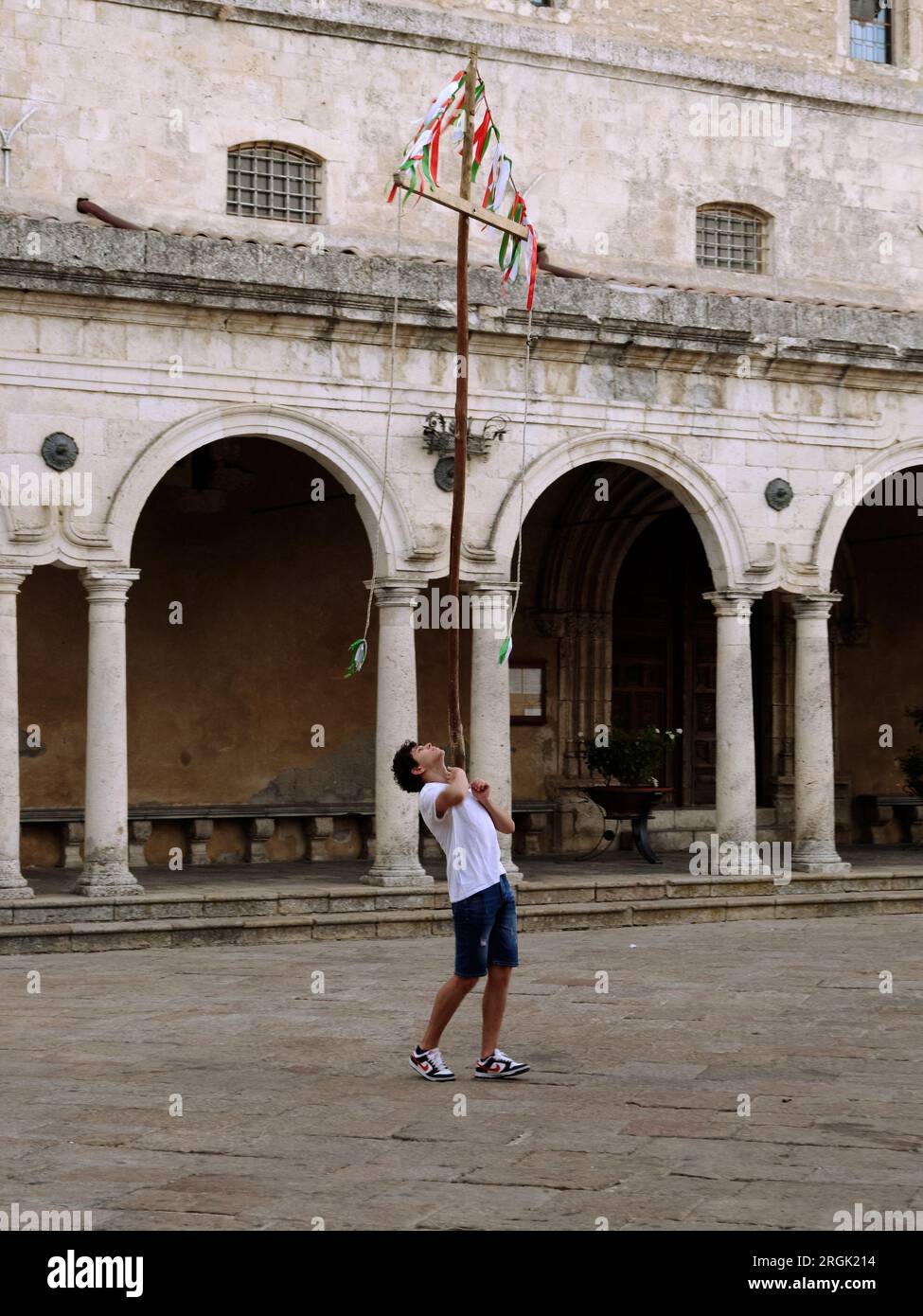 Il ragazzo adolescente sta bilanciando una croce di legno sul petto, Petralia Soprana, Sicilia, Italia Foto Stock