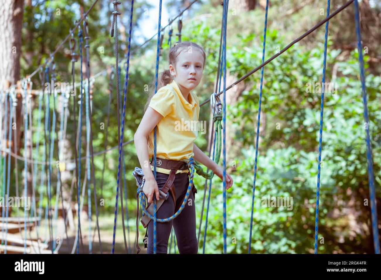 Bambini in un parco avventura nella foresta fatto di corde. Centro di animazione per arrampicata all'aperto per bambini. Parco giochi per bambini e sport con funivia. Foto Stock