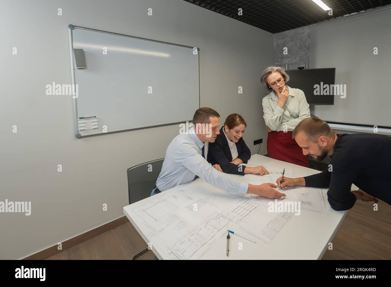 L'estrusione femminile valuta il lavoro dei subordinati. Progettisti ingegneri a una riunione. Foto Stock