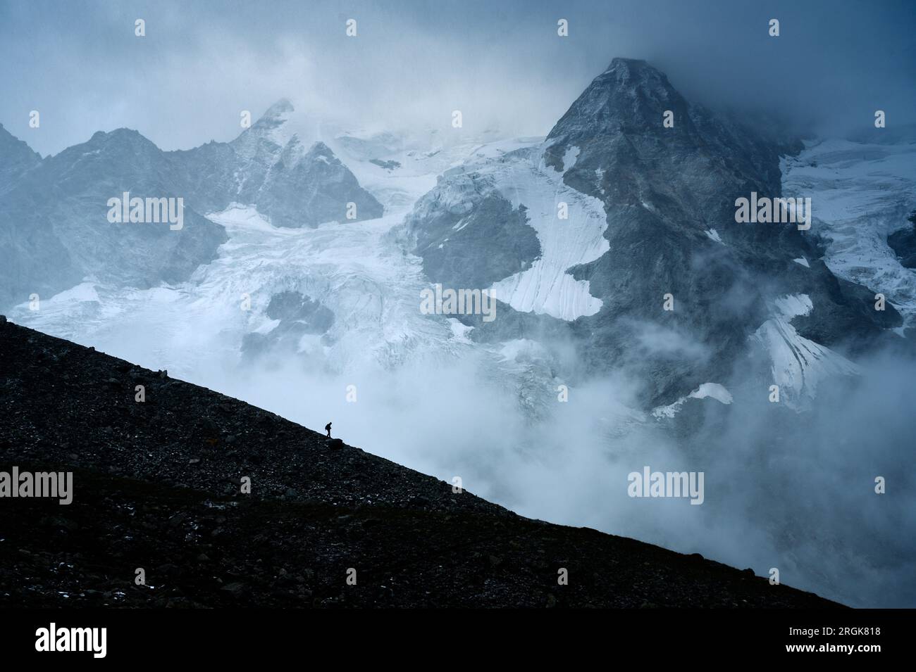 Sagoma di un escursionista di fronte ai ghiacciai e alle vette alpine della Val d'Anniviers, Vallese Foto Stock