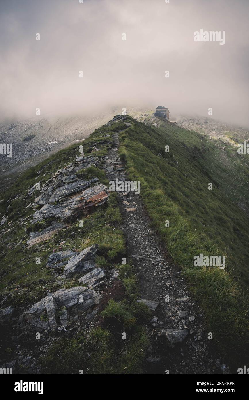 Un bel sentiero in montagna, sullo sfondo, una funivia che affonda tra le nuvole Foto Stock
