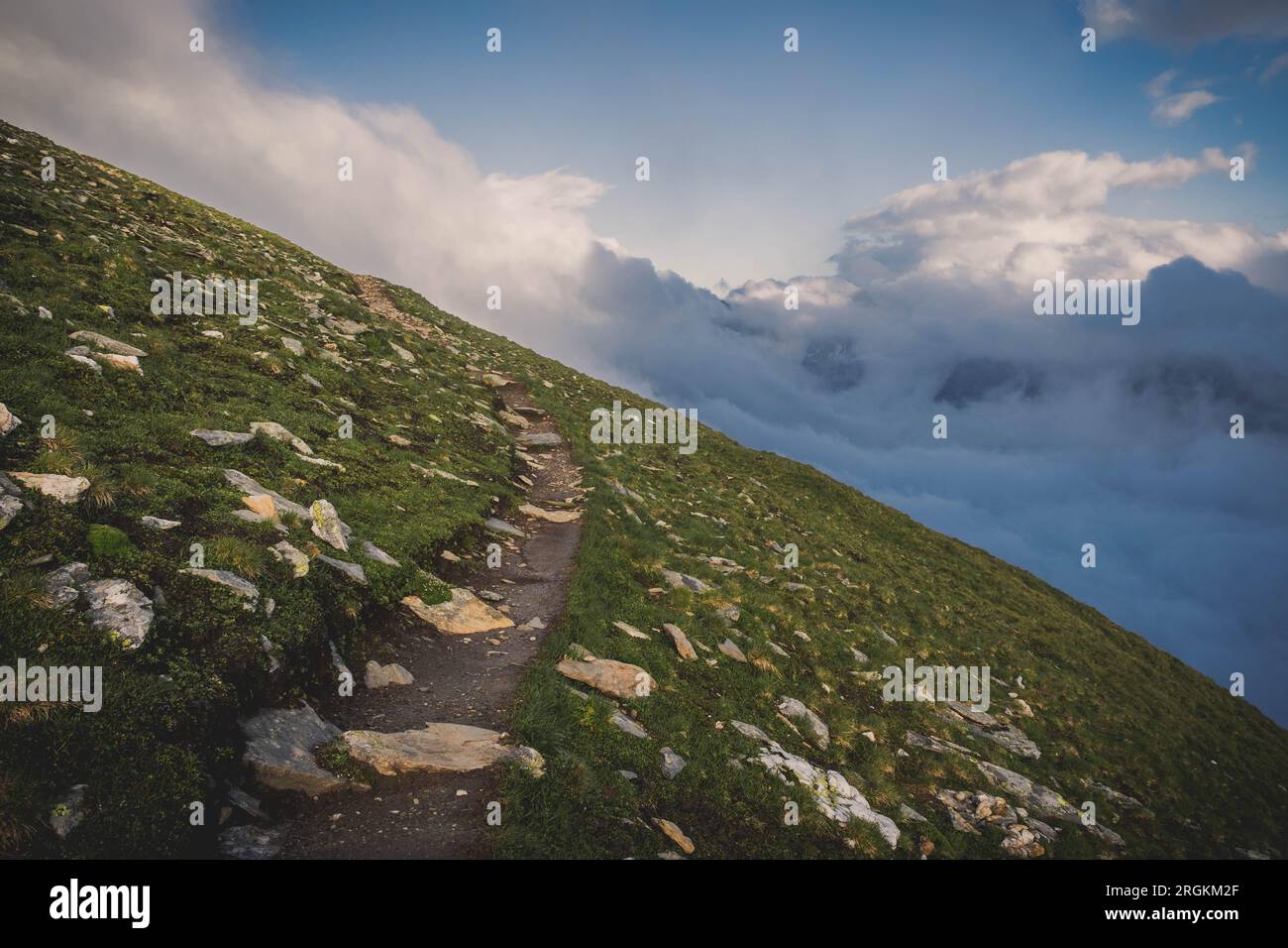Un bellissimo sentiero tra montagne, sfondo, sullo sfondo bellissime nuvole, montagne e cielo blu Foto Stock