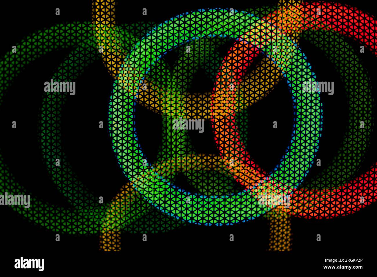 Texture dei cerchi verdi e rossi in griglia su sfondo scuro. Bagliore al buio. Sfondo disco astratto. Luce colorata. I cerchi si intersecano. Foto Stock