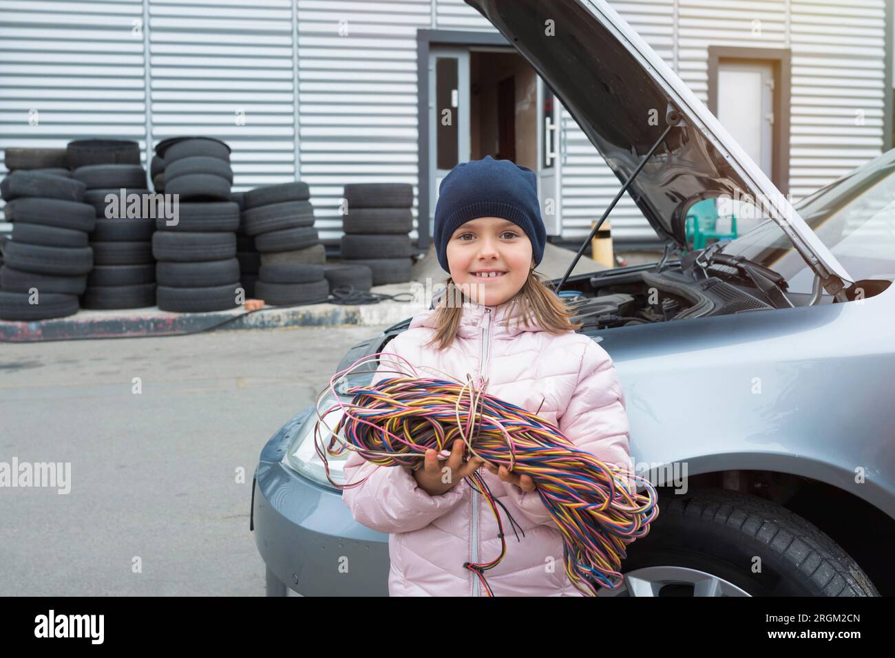 Bambina con fili sullo sfondo di un'auto. Servizio auto Foto Stock