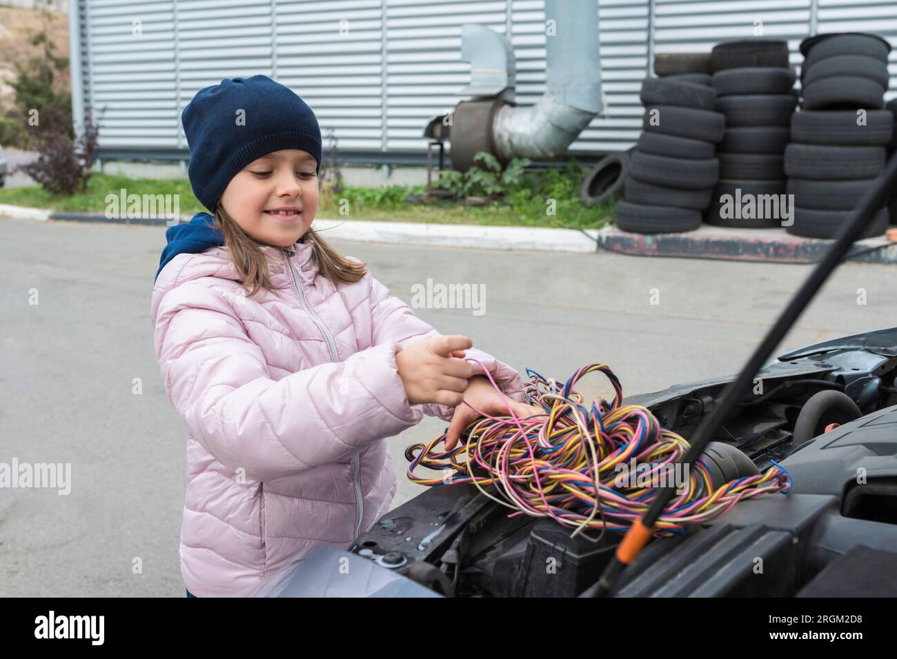 Una ragazza sta riparando un'auto. Servizio di riparazione. Servizio auto Foto Stock