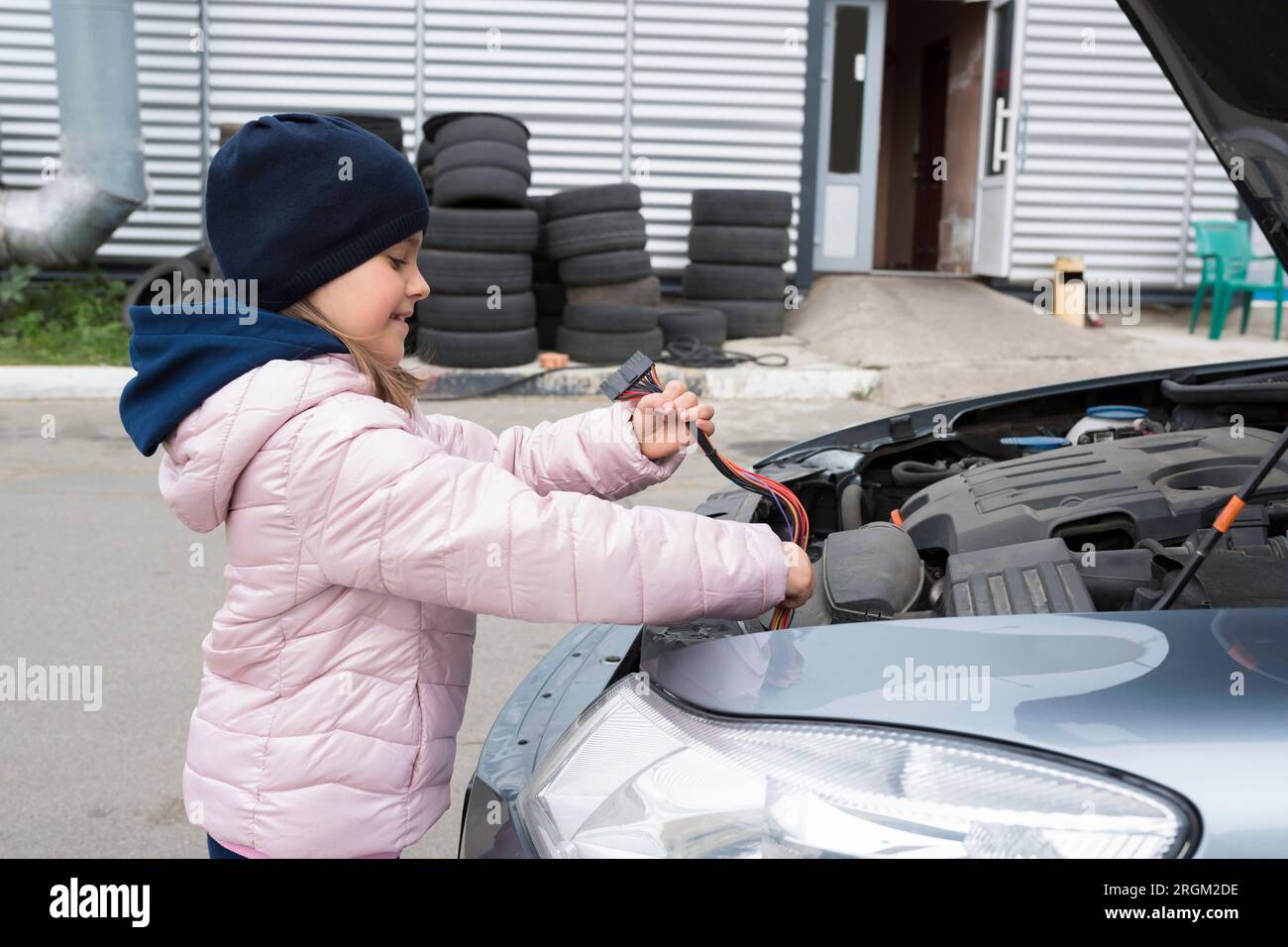 Meccanico di auto per bambini che cambia il cablaggio in un'auto. Servizio di riparazione Foto Stock