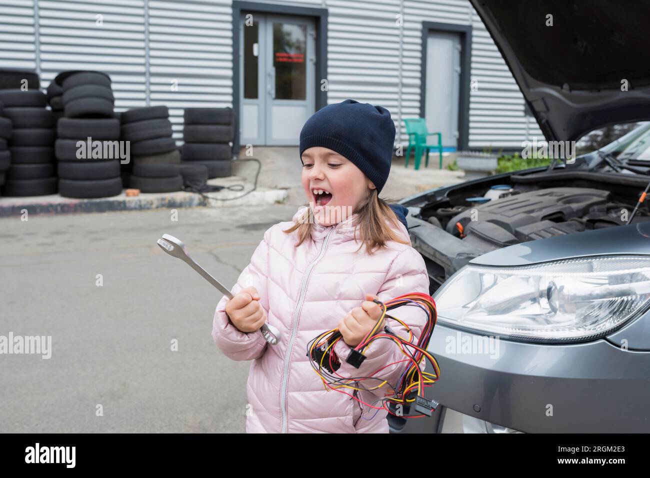 Un bambino con una chiave e un filo in mano, sullo sfondo di un servizio auto. Foto Stock