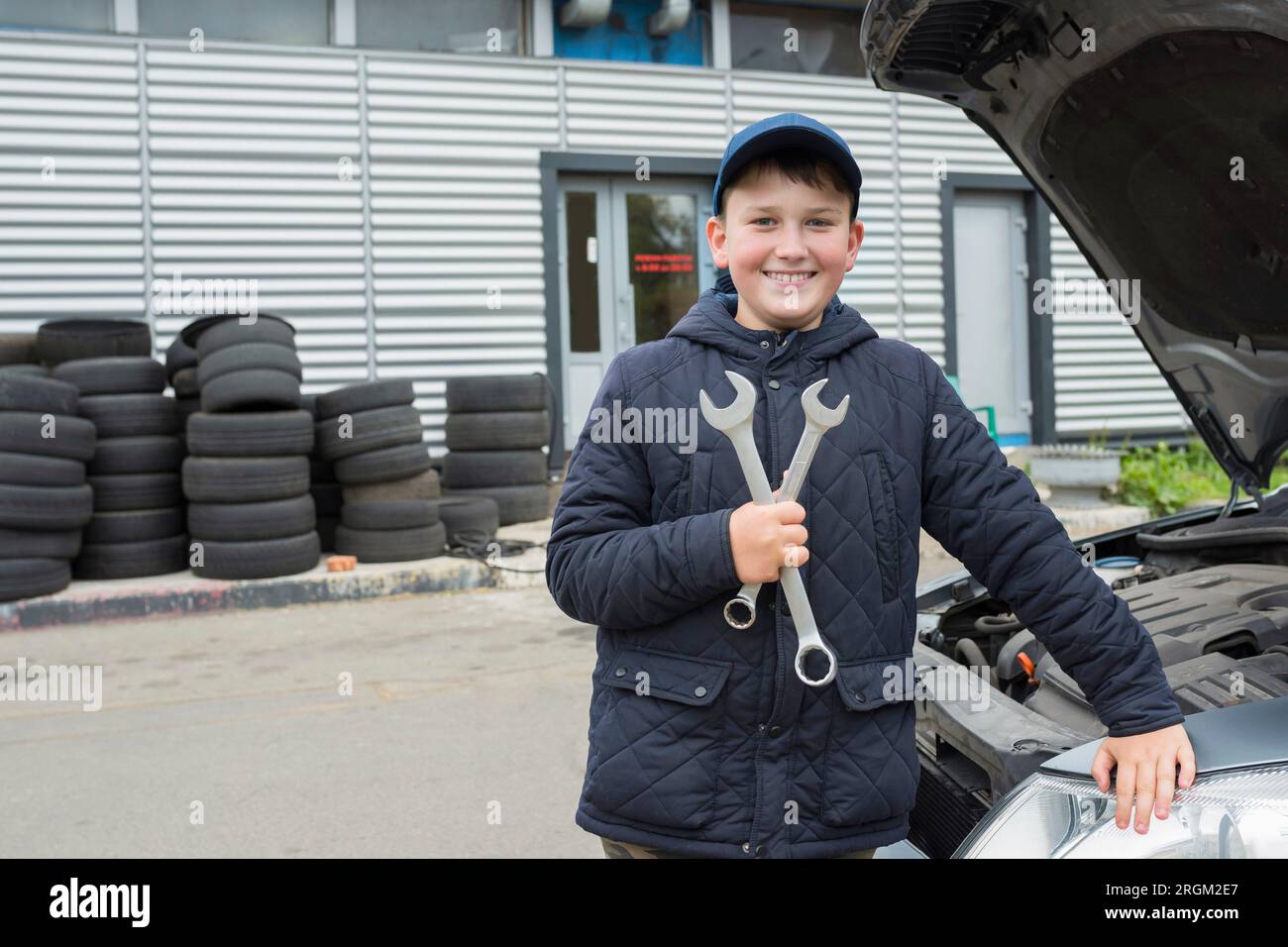 Felice ragazzo con una chiave inglese al servizio auto. Servizi di riparazione auto Foto Stock
