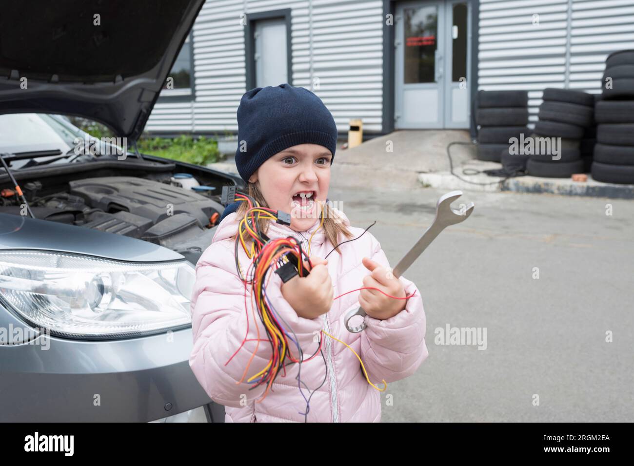 Bambina con attrezzi in mano che ripara un'auto. Foto Stock