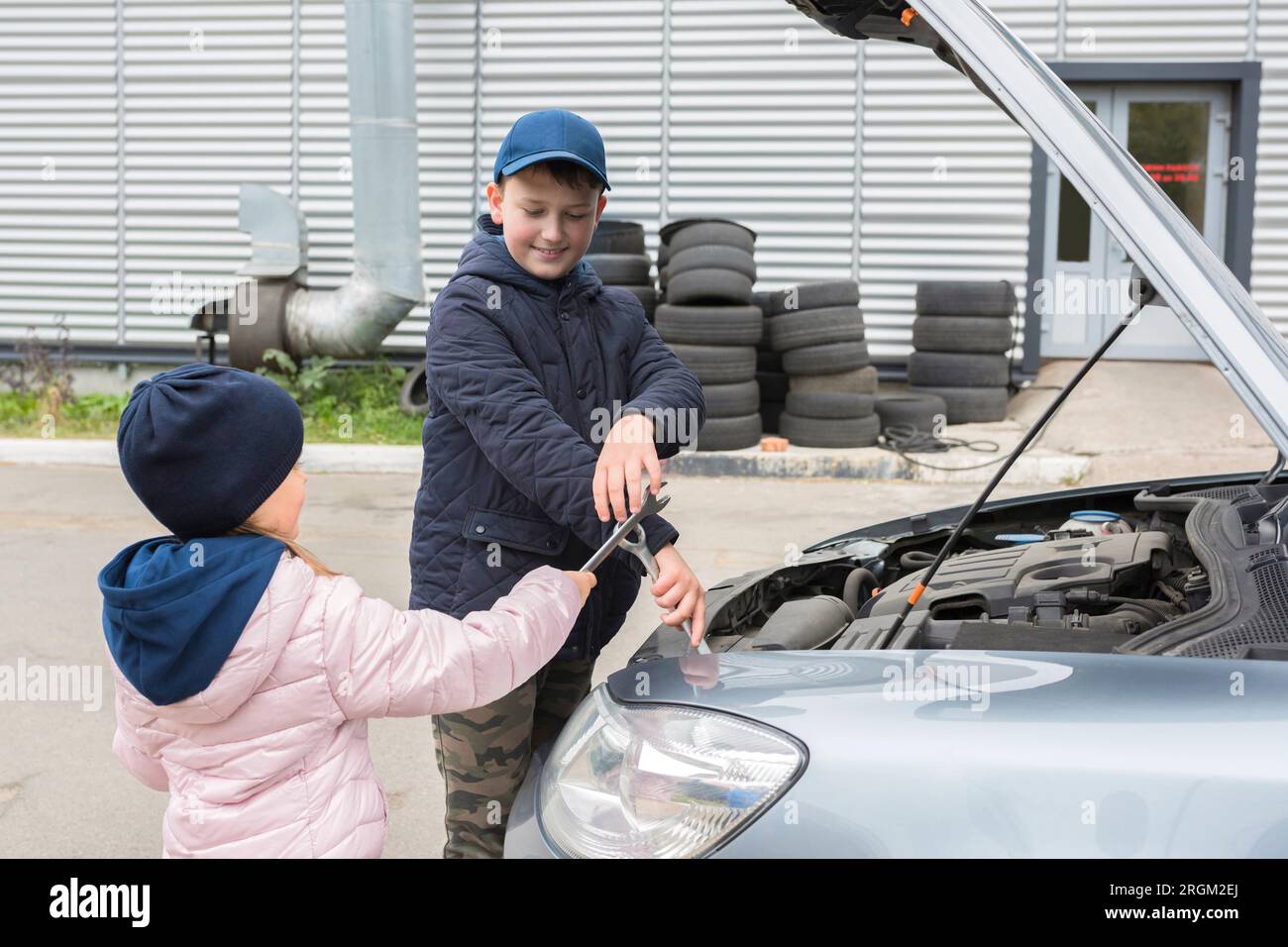 I bambini felici all'aperto stanno riparando un'auto. Servizio di riparazione Foto Stock