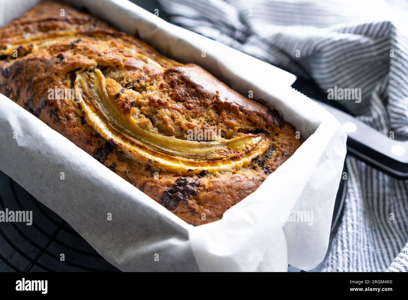 Pane alla banana appena fatto con gocce di cioccolato fondente e banana affettata sulla griglia di raffreddamento Foto Stock