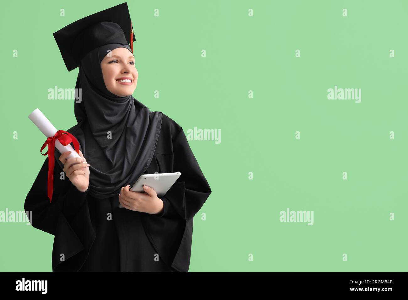 Studente laureato musulmano con diploma e tablet computer su sfondo verde Foto Stock