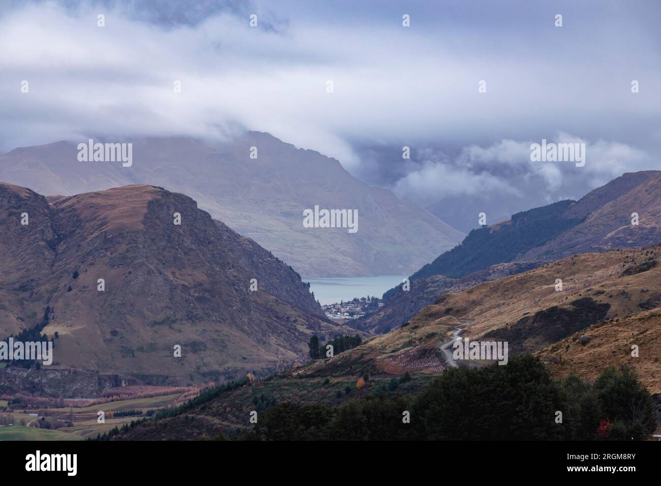Fotografa dal Coronet Peak una catena montuosa e un lago che attraversa una vallata ampia e tortuosa in una giornata nuvolosa a Queenstown, in nuova Zelanda Foto Stock