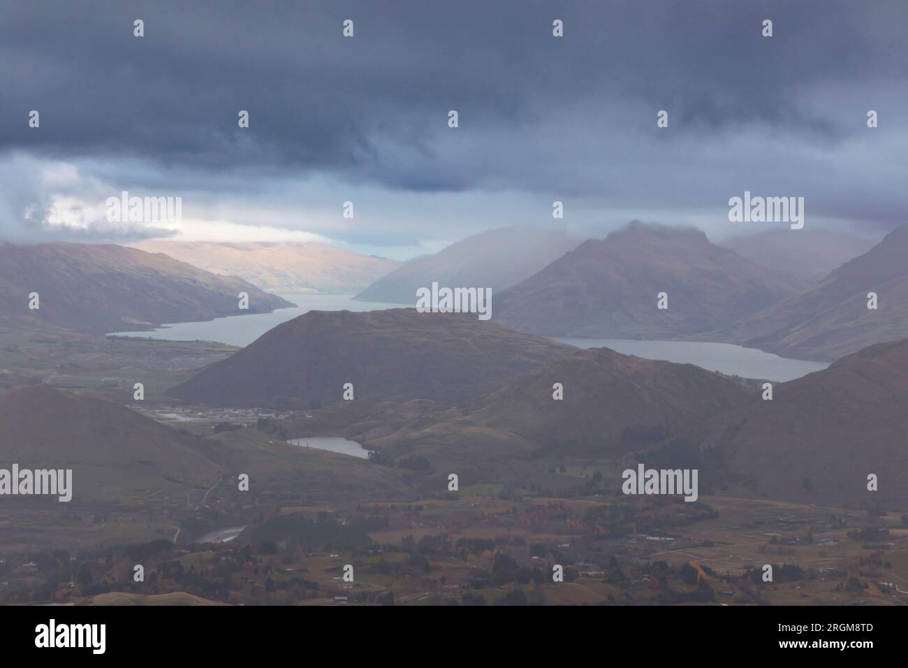 Fotografa dal Coronet Peak una catena montuosa e un lago che attraversa una vallata ampia e tortuosa in una giornata nuvolosa a Queenstown, in nuova Zelanda Foto Stock