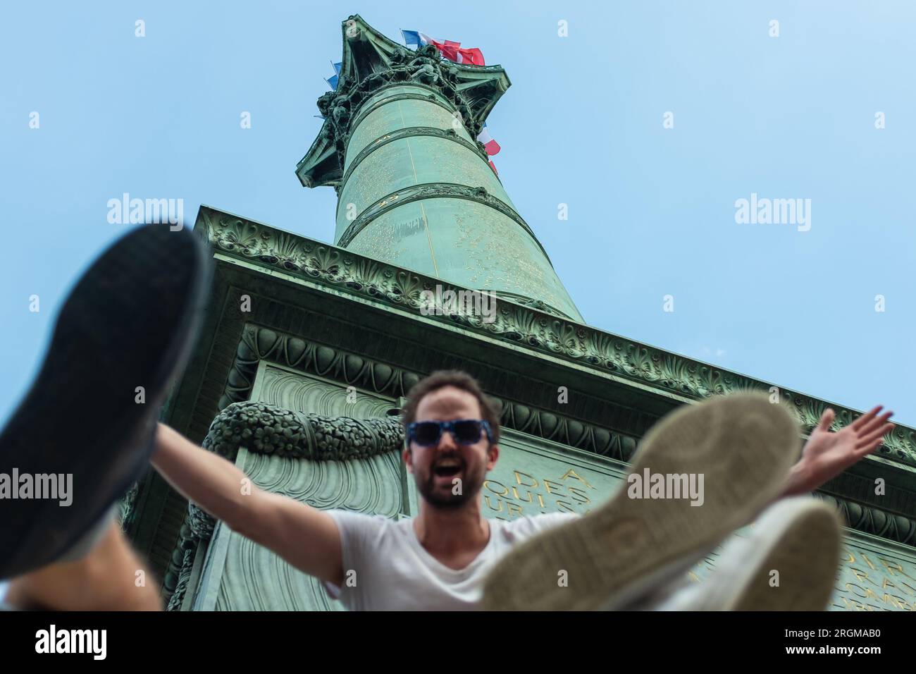 Parigi, Francia, 2018. Arroccato sulla colonna di luglio, un uomo saluta gli amici con un sorriso enorme e le braccia aperte il giorno in cui la Francia ha vinto la Coppa del mondo Foto Stock
