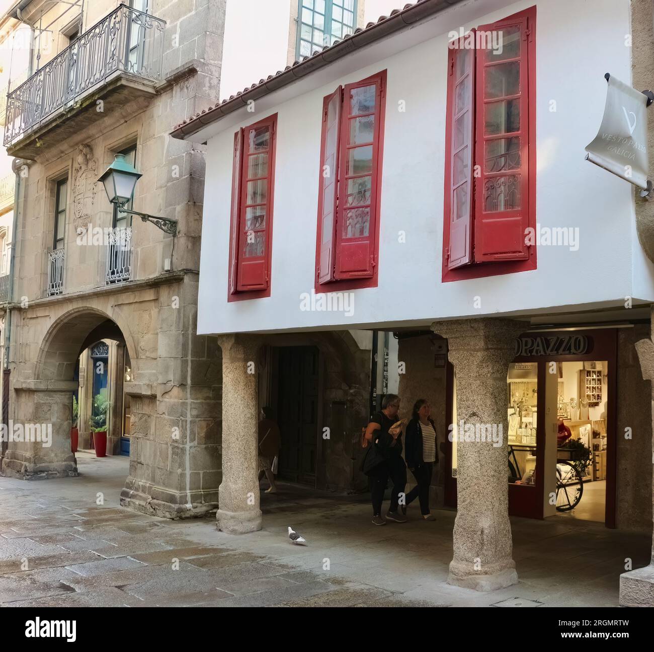 Centro storico, galleria di negozi, passaggio coperto con colonne in pietra e edificio con finestre rosse Santiago de Compostela, Galizia Spagna Foto Stock
