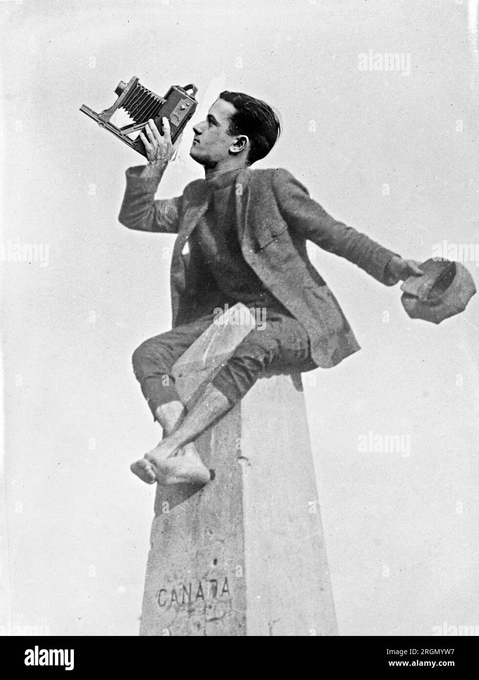 Un fotografo seduto in cima a un monumento in pietra ca. 1924 Foto Stock